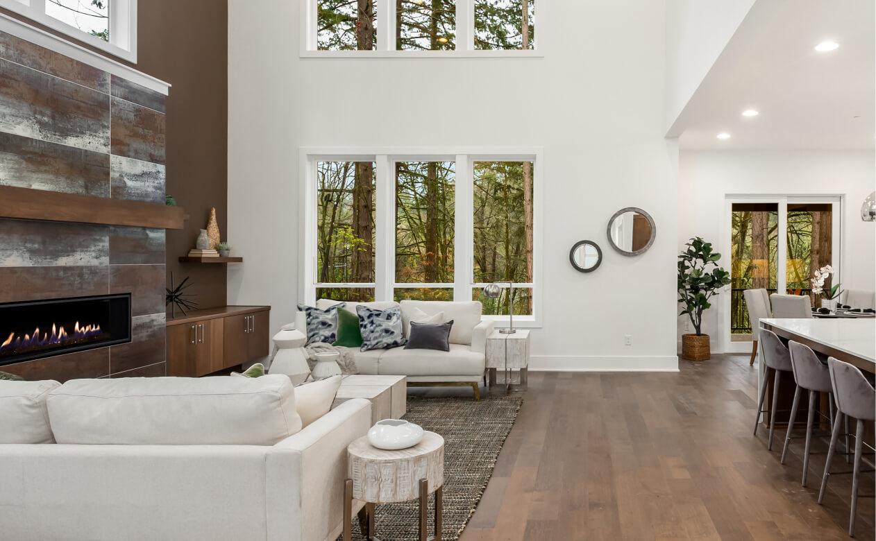 Living room, dark hardwood floors, white couches, windows.